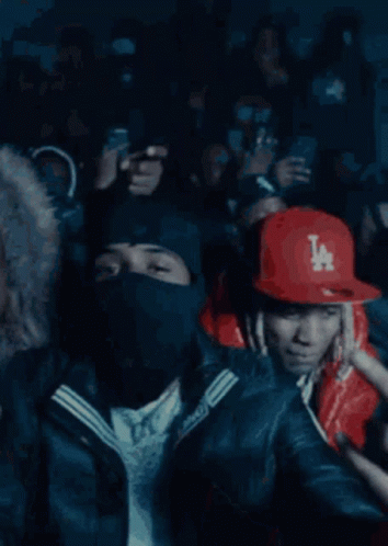 A Crowd Of People Are Gathered In A Dark Room And One Man Is Wearing A Red Jacket With A Ny Logo On It GIF