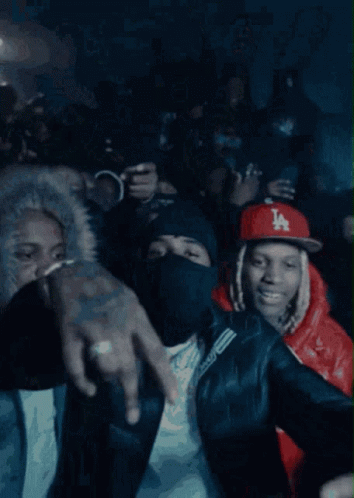 A Crowd Of People Are Gathered In A Dark Room And One Of Them Is Wearing A Ny Hat GIF
