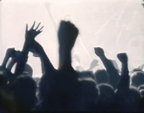 a crowd of people are raising their hands in the air