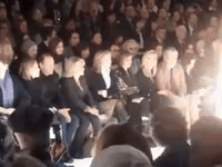 A Crowd Of People Are Sitting In A Stadium At A Fashion Show . GIF