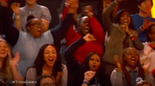 A Crowd Of People Are Sitting In A Stadium Cheering And Laughing . GIF