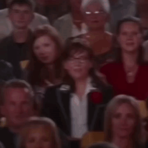 A Crowd Of People Are Sitting In A Theatre Watching A Show . GIF