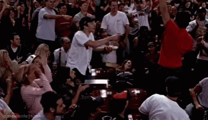 A Crowd Of People Are Watching A Game And One Man In A Red Shirt Is Pointing GIF