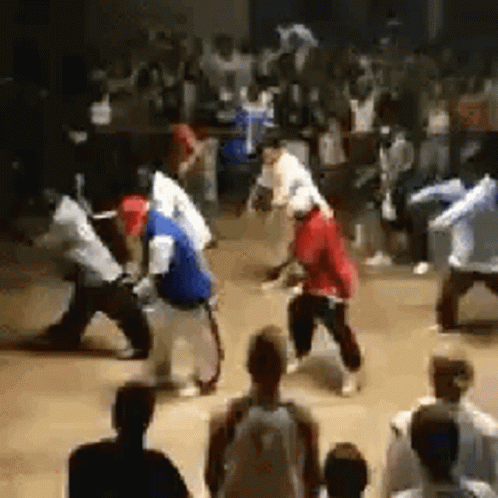 A Crowd Of People Are Watching A Group Of People Dancing In A Room . GIF