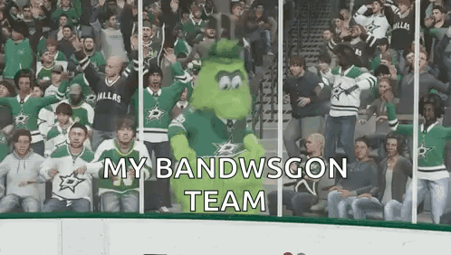 A Crowd Of People Are Watching A Hockey Game And A Mascot Is Standing In The Stands . GIF