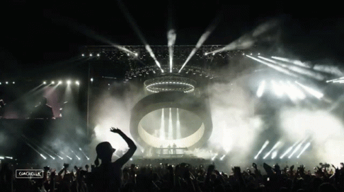 A Crowd Of People At A Concert With The Word Coachella On The Bottom Left GIF