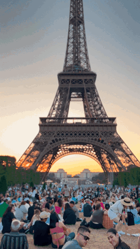 A Crowd Of People Gathered In Front Of The Eiffel Tower GIF