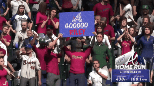 A Crowd Of People Holding Up A Sign That Says Gooooo Riley GIF