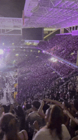 A Crowd Of People In A Stadium With Purple Lights GIF