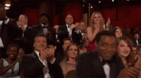 A Crowd Of People In Tuxedos Are Applauding At An Awards Ceremony . GIF