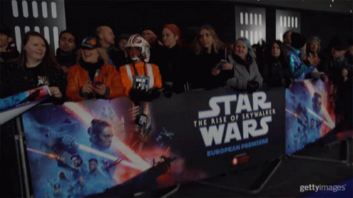 A Crowd Of People Standing In Front Of A Star Wars European Premiere Banner GIF