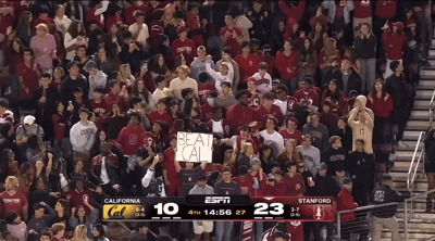 a crowd of people watching a basketball game with a sign that says beat cal