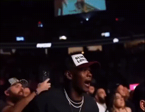 A Crowd Of People Watching A Boxing Match With One Man Wearing A Shirt That Says Kings GIF