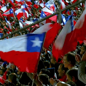 A Crowd Of People Waving Red White And Blue Flags Including A Flag With A Star On It GIF