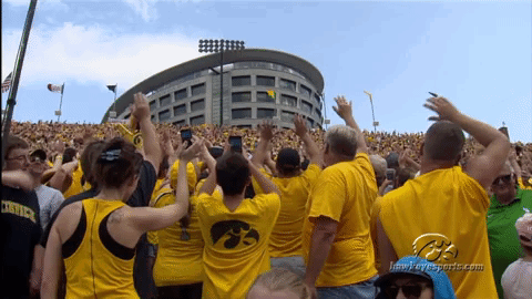 A Crowd Of People Wearing Yellow Shirts With A Hawkeyes Logo On The Back GIF