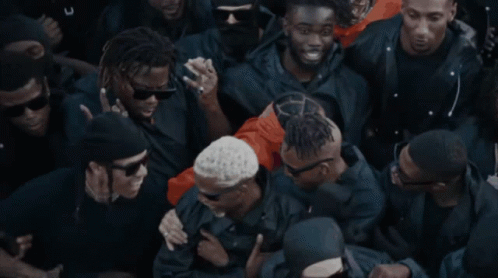A Crowd Of People With One Wearing Sunglasses And A Necklace That Says Armour GIF