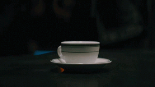 A Cup Of Coffee On A Saucer With A Black And White Stripe GIF