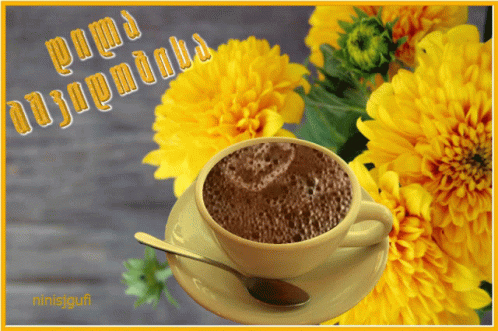A Cup Of Coffee Sits On A Saucer With Yellow Flowers In The Background And A Greeting In A Foreign Language GIF