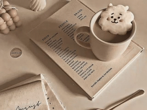 A Cup Of Coffee Sits On Top Of A Book That Says People GIF