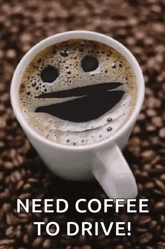 A Cup Of Coffee With A Smiley Face On It Is Sitting On A Pile Of Coffee Beans . GIF