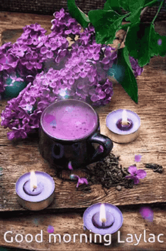 A Cup Of Purple Tea Surrounded By Purple Flowers And Candles On A Wooden Table . GIF