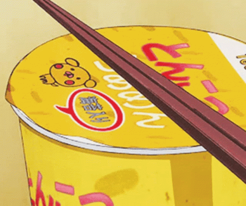 A Cup Of Ramen With Chopsticks Sticking Out Of The Top GIF