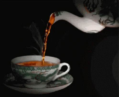 A Cup Of Tea Is Being Poured From A Tea Kettle GIF