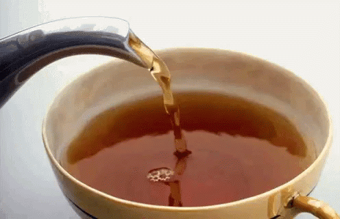 A Cup Of Tea Is Being Poured From A Teapot Into It GIF