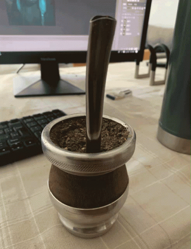 A Cup Of Yerba Mate Sits On A Table Next To A Computer Monitor GIF