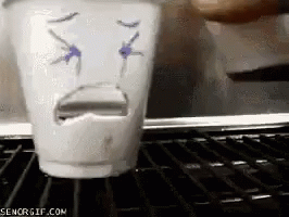 A Cup With A Face Drawn On It Is Sitting On A Shelf GIF