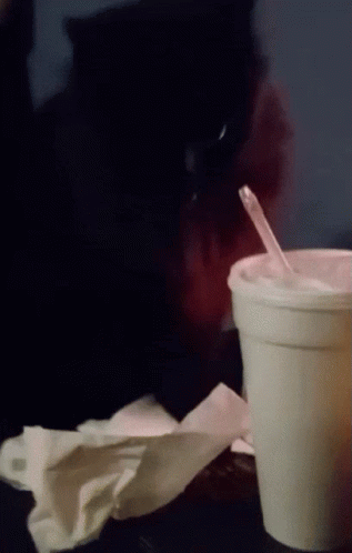A Cup With A Straw In It Sits On A Table GIF