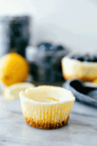 A Cupcake Is Sitting On A Table With Lemons And Blueberries In The Background GIF