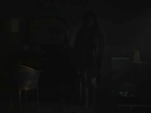 A Dark Room With A Chair And A Lamp On GIF