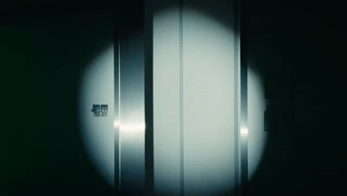 a dark room with a light shining on a door that says ' emergency exit ' on it