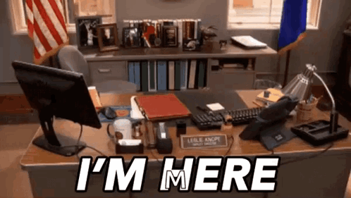 A Desk With A Computer And A Sign That Says I 'M Here On It GIF