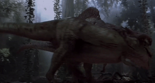 A Dinosaur Is Walking Through A Dark Forest With Trees In The Background GIF