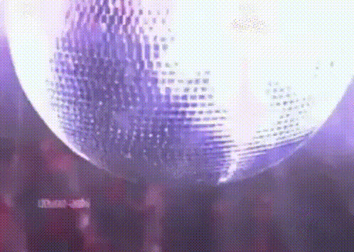 A Disco Ball Is Spinning In A Dark Room With Purple Lights . GIF