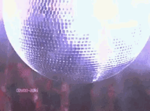 A Disco Ball Is Spinning In The Air In A Dark Room . GIF