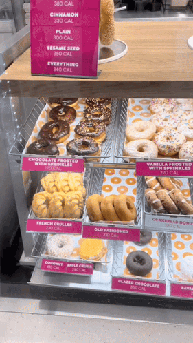 A Display Case Of Donuts With A Sign That Says 360 Calories On It GIF