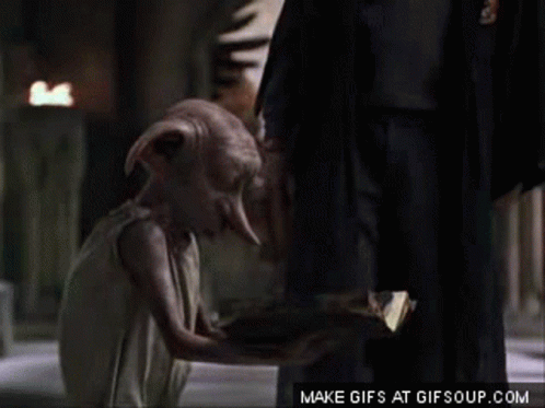 A Dobby From Harry Potter Is Kneeling Down Next To A Man In A Suit . GIF