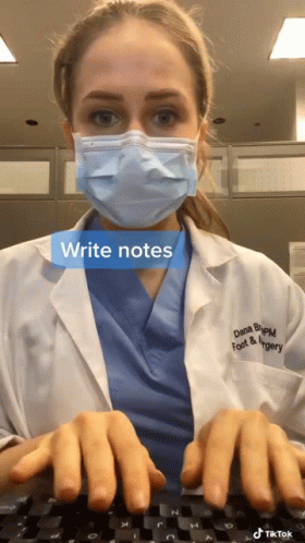 A Doctor Wearing A Mask And Scrubs Is Typing GIF