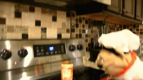 A Dog Wearing A Chef 'S Hat Is Cooking On A Stove Top GIF
