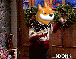 A Dog Wearing A Sweater Is Holding A Wreath In Front Of A Door That Says $ Bonk On It GIF