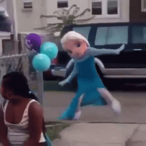 A Doll Dressed As Elsa From Frozen Is Walking Down A Sidewalk GIF
