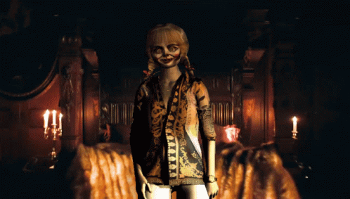 A Doll In A Leopard Print Shirt Stands In A Dark Room With Candles GIF