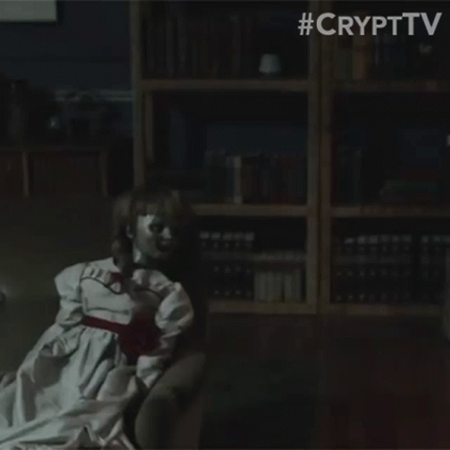 A Doll Is Sitting In A Dark Room With A Bookshelf In The Background . GIF