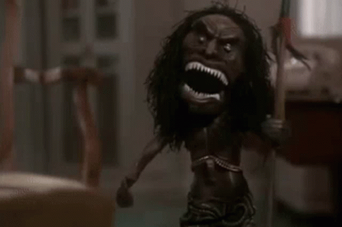 a doll with a long haired head is holding a spear in a room .