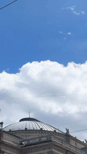 A Dome Shaped Building With A Blue Sky And Clouds Behind It GIF