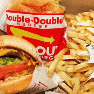 A Double-Double Burger And French Fries Are Sitting On A Table GIF