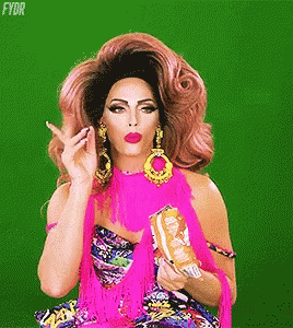 A Drag Queen In A Pink Dress Is Holding A Bag Of Chips And Making A Funny Face . GIF